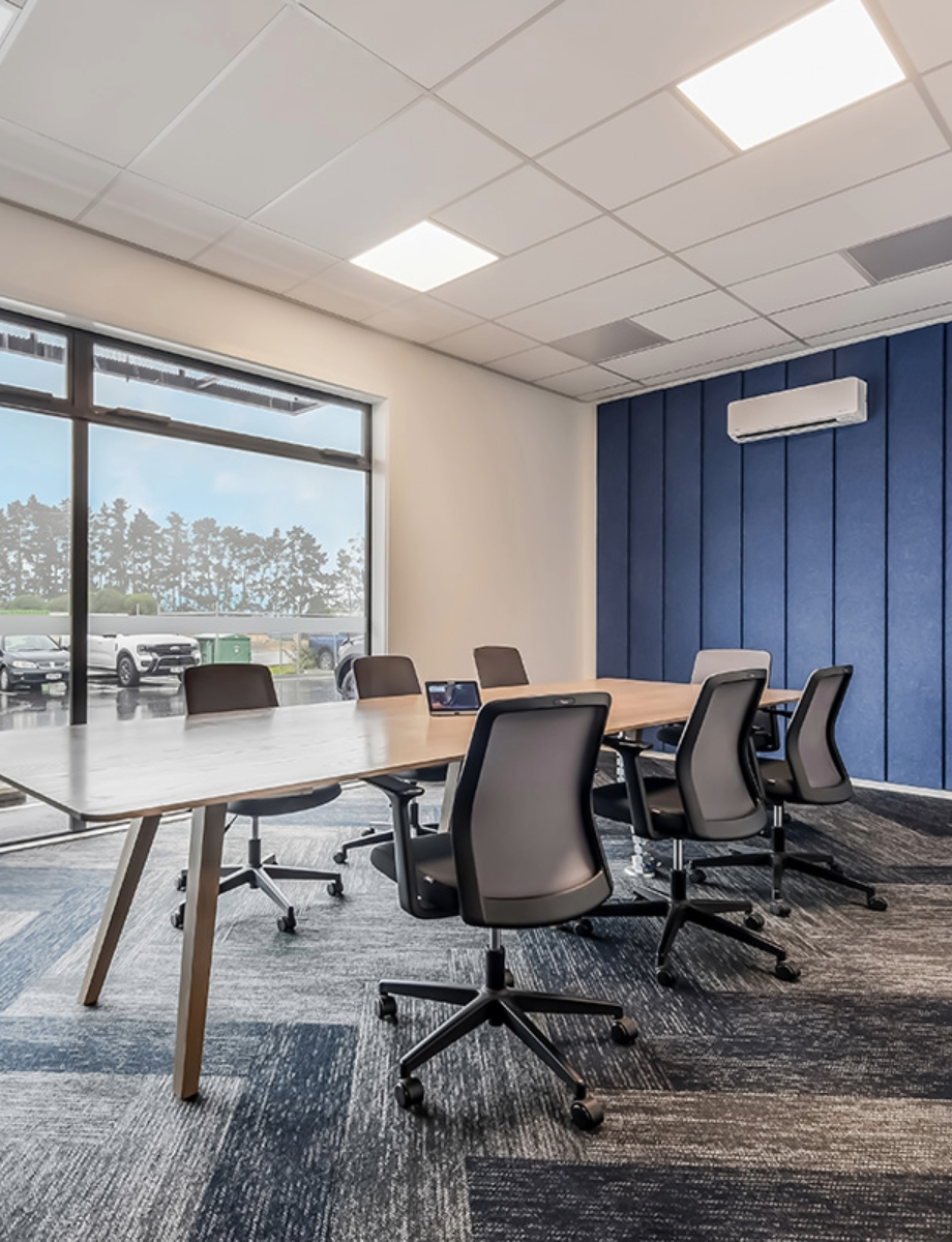 Modern commercial interior meeting room with blue acoustic wall panels, natural light, and ergonomic chairs, designed for professional office fit outs