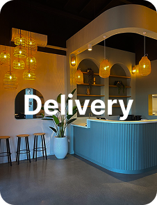 Elegant restaurant reception with a curved grey counter, warm pendant lights, arched shelving, and a potted plant
