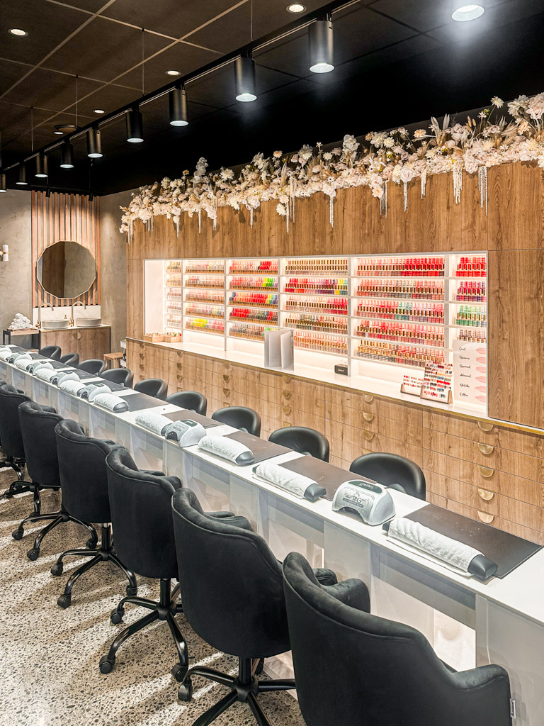 Nail salon in Christchurch with multiple nail stations along the room with nail polish display behind. 