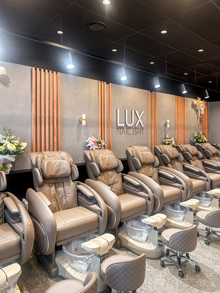 Multiple massage chairs against the wall in a nail salon.