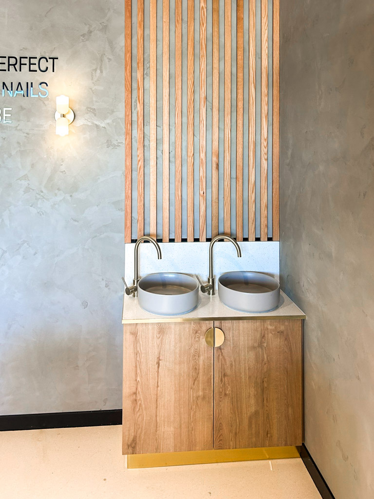 Basin with wooden cupboard fronts and featured wall in a new retail interior fitout.