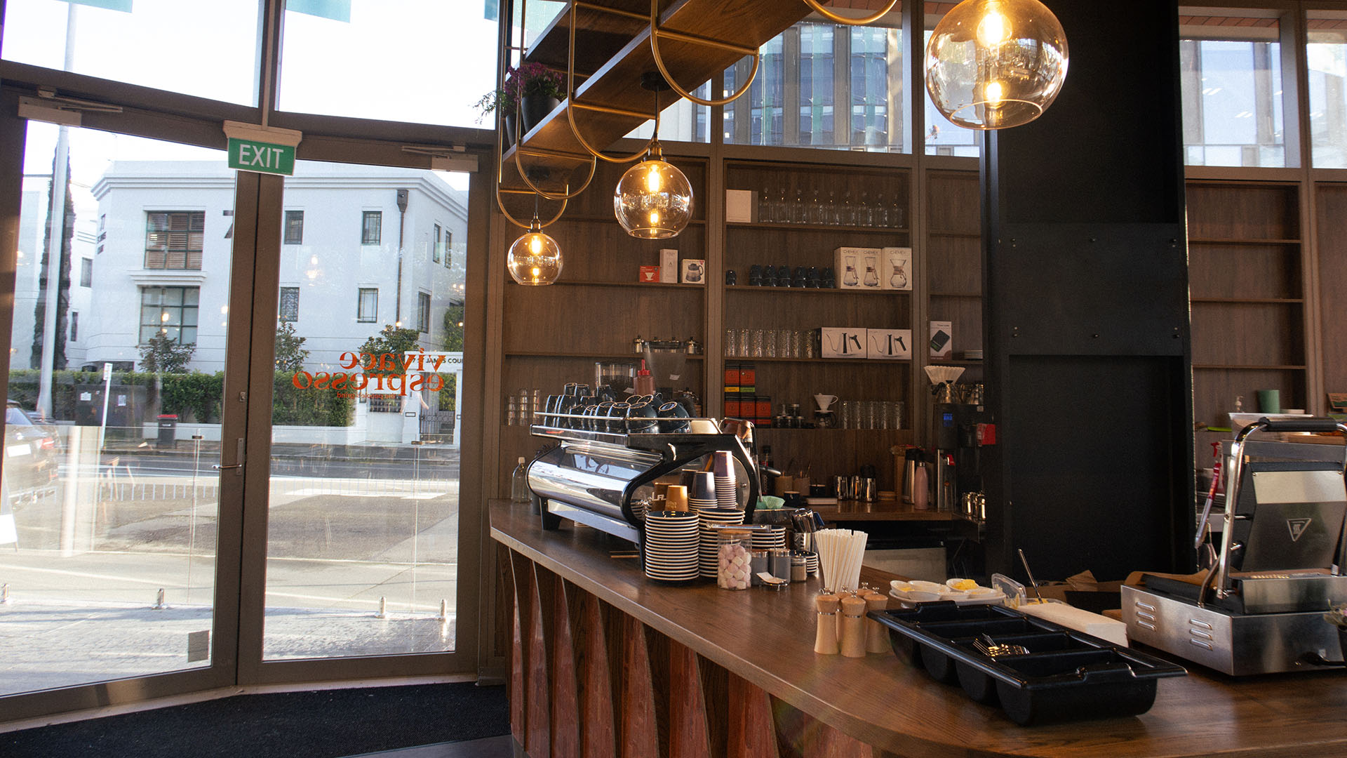 Cafe counter with a coffee machine on a timber counter top, and warm down lights.